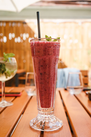 A vertical closeup shot of berry smoothie on wooden tableの写真素材