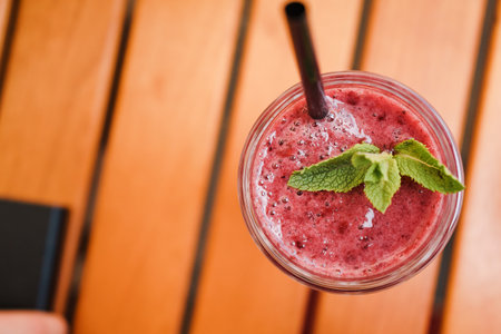 A closeup shot of berry smoothie on wooden tableの写真素材