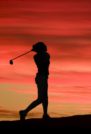 Silhouette of a young woman playing golf on the evening sky with pink shadesの写真素材