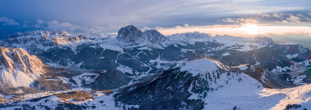 A panoramic shot of mountains covered in snow at sunsetの写真素材