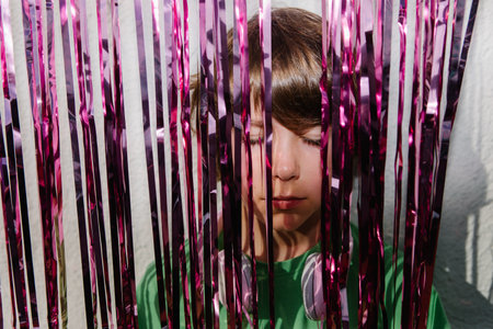 A young American boy with his eyes closed wearing headphones near the purple confetti tapes