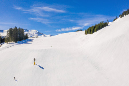 A ski area with skiers sliding down the snow-covered slope under a blue sky
