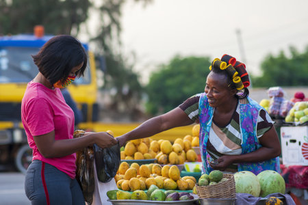 An African American female in a protective face mask shopping for fruit at a market