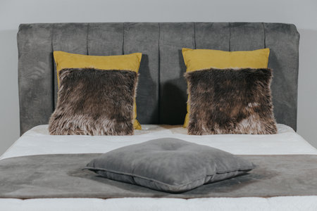 A closeup shot of a bed with gray fabric upholstery and stylish pillowsの写真素材
