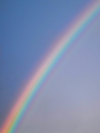 A vertical beautiful shot of rainbow on blue skyの写真素材