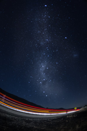 A vertical shot of the blurred car lights in the street and a sky with stars at nightの写真素材