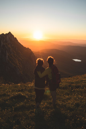 A young couple enjoying the sunset from the top of a mountainの写真素材
