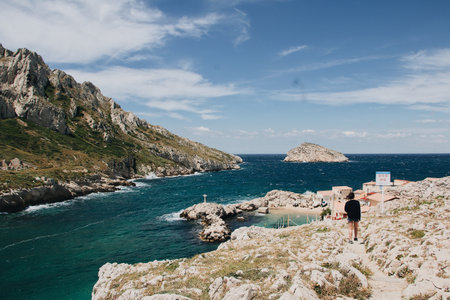 A beautiful view of huge rocks and quite sea with a young female wandering around, Marseille, France