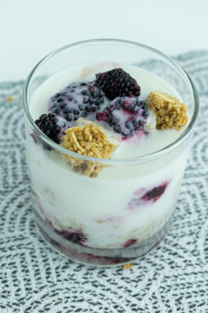 A closeup shot of a glass of fresh parfait with blackberry and granola on the table, healthy...