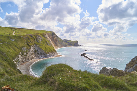 A beautiful shot of Lulworth Cove, UK under blue sky and white clouds