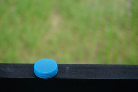 A selective focus shot of a plastic water bottle cap on a wooden surface with a blurred backgroundの写真素材