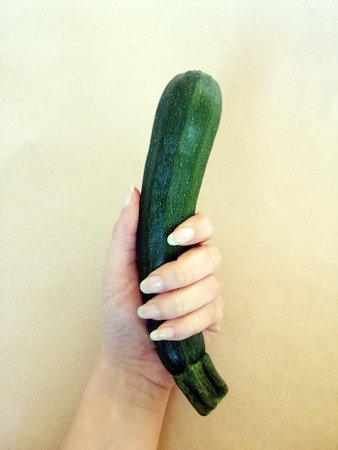 A vertical picture of a female holding a zucchiniの写真素材