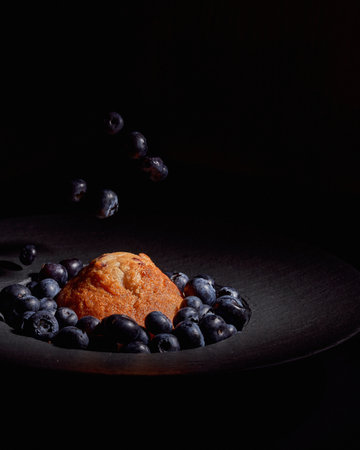 A closeup of a cupcake with blueberries in a black plate - Perfect backdrop for restaurants