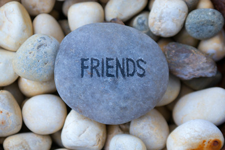 The word FRIENDS written on a grey pebble among smaller pebblesの写真素材