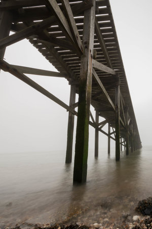 A low angle shot of the wooden pier under a scenic cloudy skyの写真素材