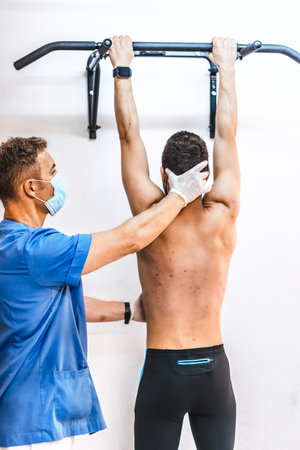 A physiotherapist with a face mask helping a young male with his recovery