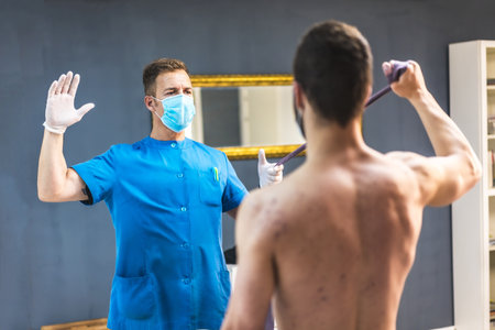 A physiotherapist working with the sportsman on his recovery