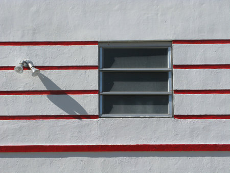A beautiful shot if a white building wall with red stripes and a small windowの写真素材