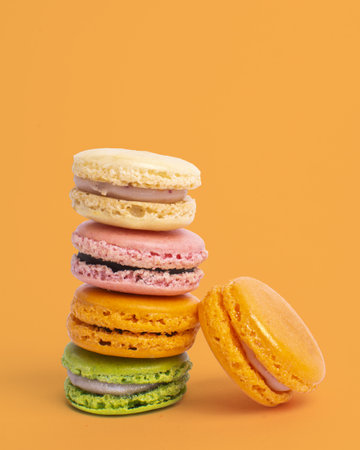 A vertical shot of colorful balancing macaroons against a yellow backgroundの写真素材