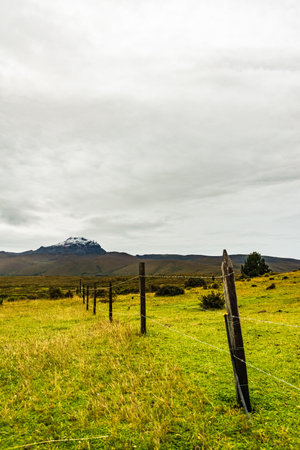 A mountain with snow on its summit with a cloudy sky over itの写真素材
