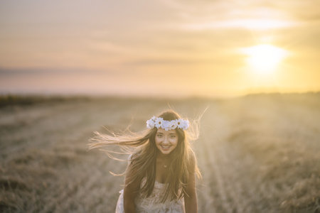 A beautiful woman wearing a white dress, a white flower headband and smiling for the camera