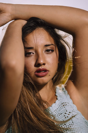 A vertical shallow focus shot of a beautiful young caucasian female posing in a field of sunflowersの写真素材