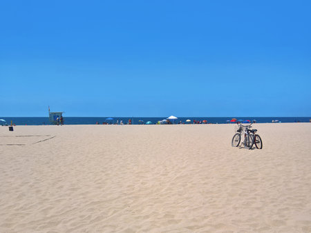 Two bicycles parked on the beach with a group of people in the backgroundの写真素材