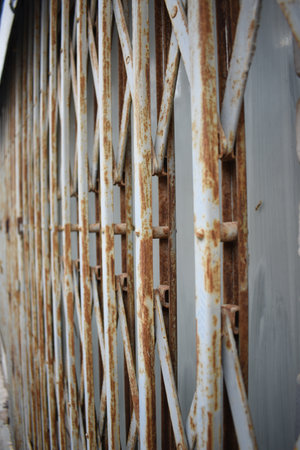 A vertical closeup shot of an old rusty white gateの写真素材