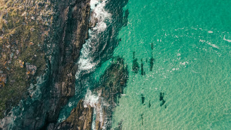 An aerial shot of rocky cliffs near a turquoise seascape