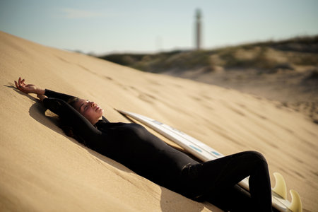 A young beautiful surfer female on the beach at sunsetの写真素材