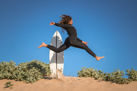 A young beautiful surfer female on the beach at sunset