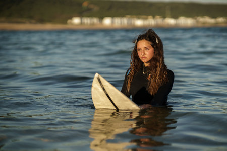 A young beautiful surfer female on the beach at sunsetの写真素材