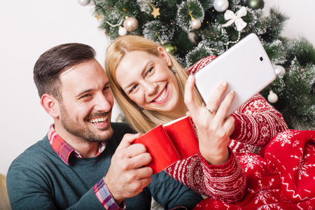 A happy couple doing a selfie on a background of Christmas tree