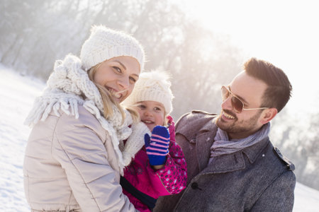 A happy family and their little daughter enjoying a beautiful and cold winter dayの写真素材