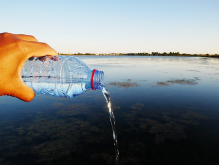 A closeup shot of a plastic water bottle in a human hand-perfect for water waste conceptの写真素材
