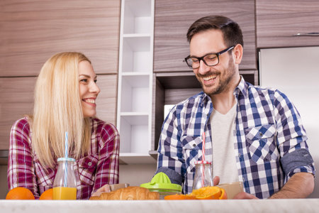 A happy couple making natural orange juice in the kitchen and enjoying their timeの写真素材