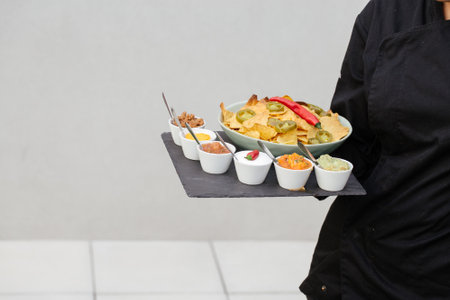 A waiter holding a plate with nachos and different saucesの写真素材