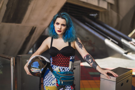 The attractive and beautiful woman with blue hair, holding a motorcycle helmet
