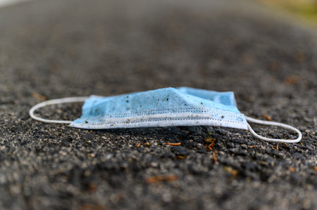 A closeup shot of a dirty medical protective face mask on the ground