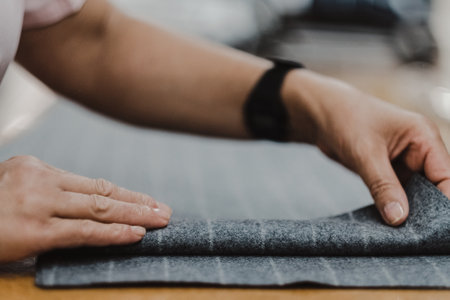 A closeup shot of tailor's hands making pants with gray fabricの写真素材