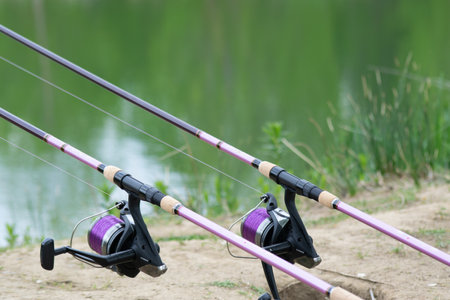 A closeup shot of two fishing rods on a river bankの写真素材