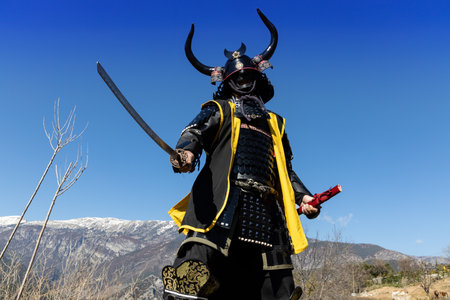 A Japanese Samurai warrior dressed in armor with a mesmerizing mountainous backgroundの写真素材