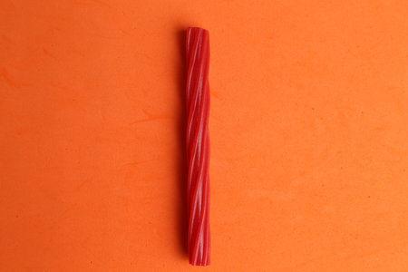 A closeup shot of a red licorice candy on an orange backgroundの写真素材