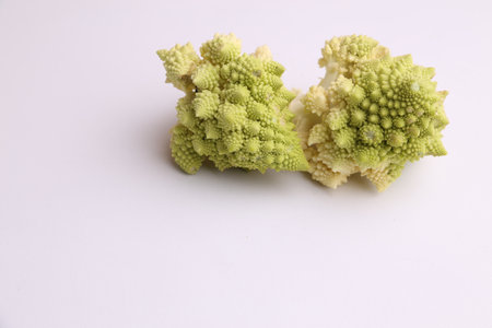 A closeups shot of two pieces of fresh romanesco broccoli on a white surfaceの写真素材