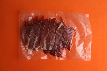 An overhead shot of raw beef meat in a plastic bag on a monochrome background