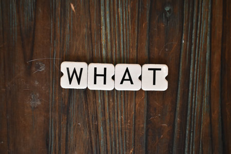 The word What written with white plastic letters on a wooden surface