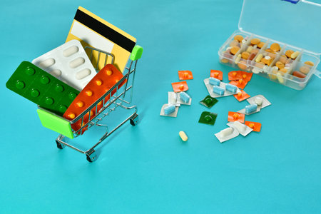 A miniature shopping cart with medicines on blue backgroundの写真素材