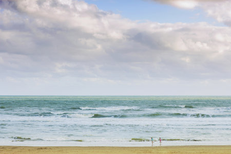 The children playing at the beach under the cloudy morning skyの写真素材