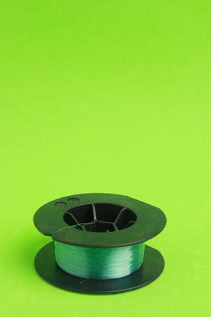 A vertical shot of a metal wire spool isolated on a green background