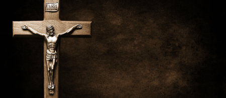 A wooden crucifix with Jesus Christ's body on it on a brown wallの写真素材